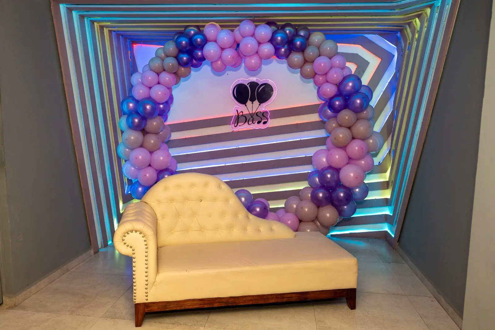 Sillón decorativo frente a un arco de globos y el muro LED del salón