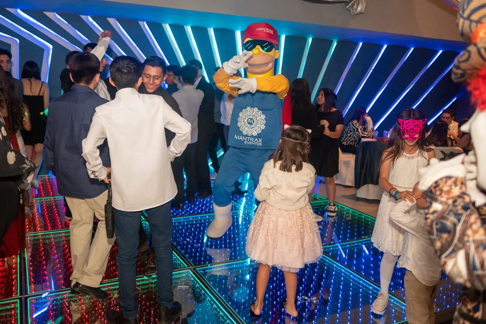 Invitados y una botarga bailando sobre la pista de luz LED
