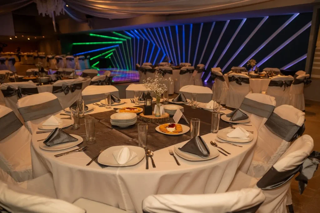 Mesa redonda montada con mantelería, loza, cristalería y cubiertos lista para el servicio de banquete