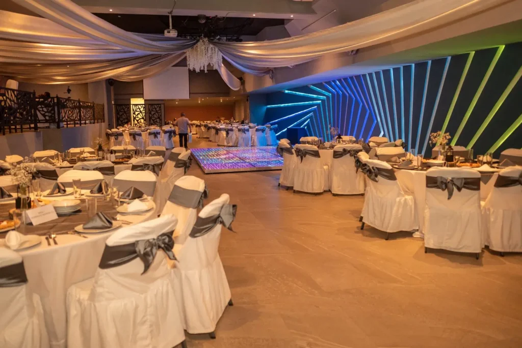 Salón Bass montado con mesas redondas, mantelería blanca y muro LED encendido al fondo